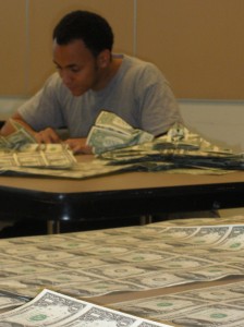 Sipho Mabona folding sheets of US dollar bills at JANM, March 2010